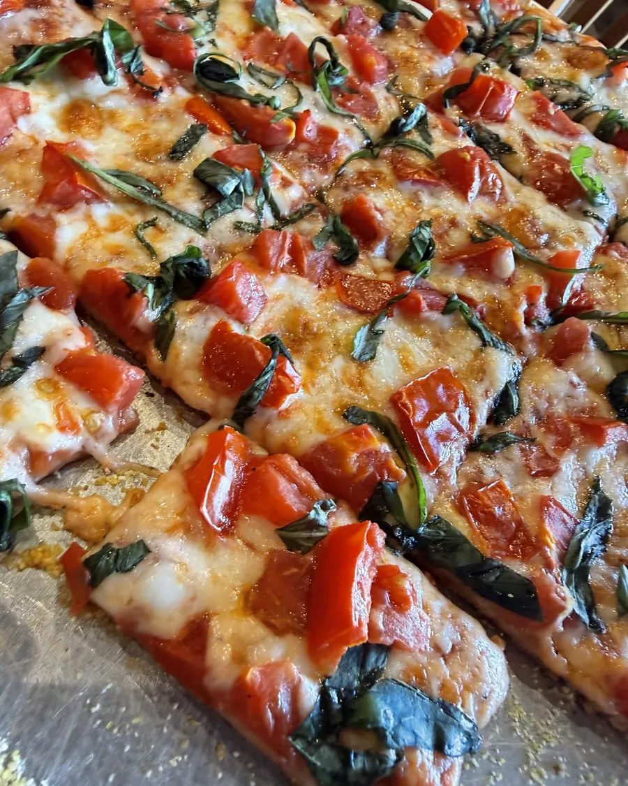 A square-cut pizza topped with tomato, fresh basil and mozzarella