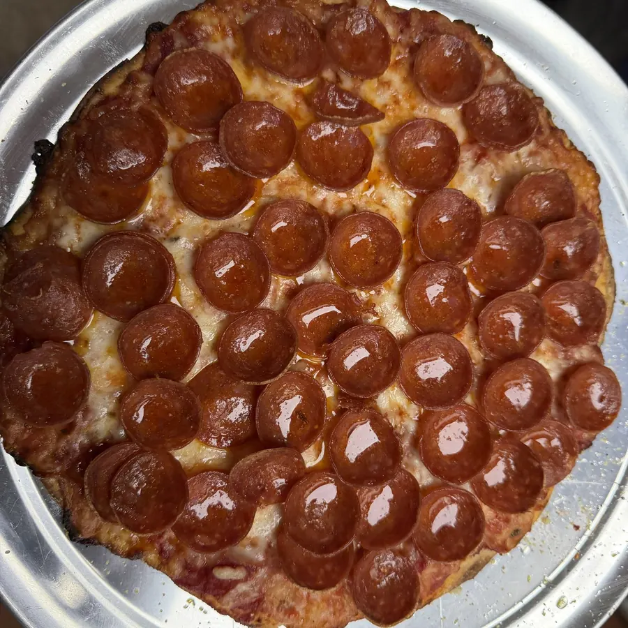 A pepperoni tavern-style pizza seen from above on a metal tray